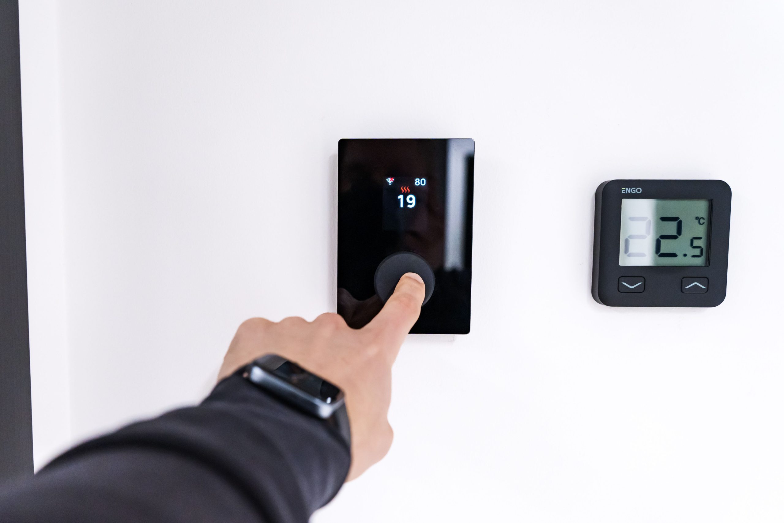Main réglant un thermostat connecté dans maison moderne